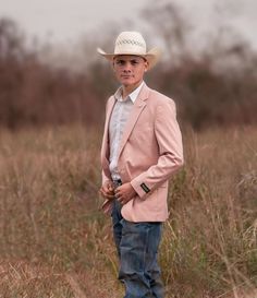 a man in a pink suit and cowboy hat standing in the middle of a field