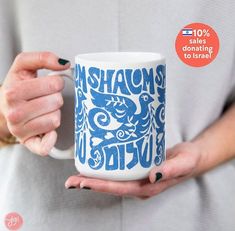 a woman holding a coffee mug with the words shatams in blue on it