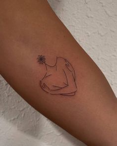 a woman's arm with a small flower tattoo on the left side of her arm