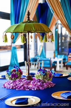 an umbrella with tassels on top of it sitting on a blue table cloth