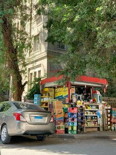 a car parked in front of a food stand on the side of a road next to a tree