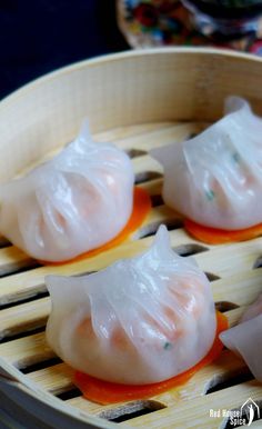 four dumplings are sitting in a bamboo steamer with orange sauce on the top and bottom