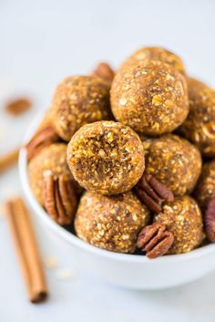 a white bowl filled with pecans and cinnamons on top of a table next to some cinnamon sticks