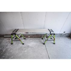 two metal benches sitting next to each other in a room with cement flooring and white walls