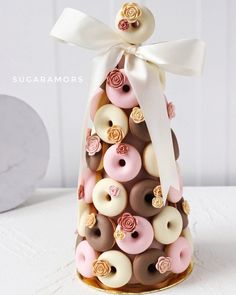 there is a small tower made out of doughnuts that are decorated with ribbons