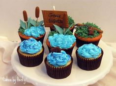 cupcakes decorated with blue frosting on a white cake platter that says gone fishing