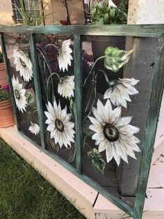 an old window with flowers painted on the glass and some potted plants behind it