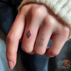 a person's hand with a small tattoo on the middle finger and an outline of a diamond