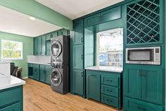 a kitchen with green cabinets and a washer and dryer in the middle of it