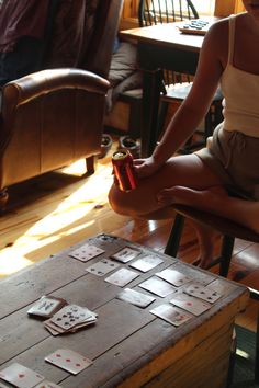 a woman sitting on top of a wooden table next to a box filled with playing cards