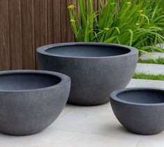 three cement planters sitting on top of a white tile floor