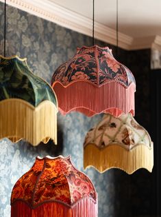 three colorful umbrellas hanging from the ceiling in a room with blue wall papered walls