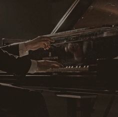 a man is playing the piano while wearing a suit and holding his hand on the keys