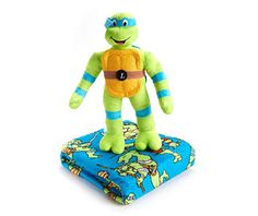 a stuffed turtle sitting on top of a blue and green blanket next to a white background