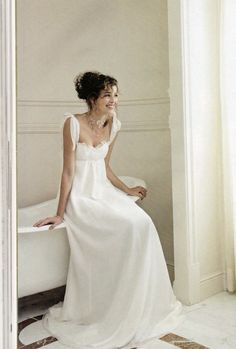 a woman in a white dress sitting on a bathtub