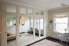 a large mirrored closet in a home with white walls and doors that lead into the dining room