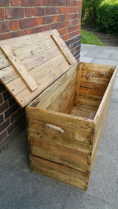 a wooden box sitting on the sidewalk next to a brick wall with a door open