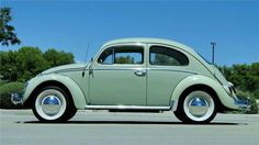 an old green car parked in a parking lot