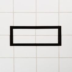 a black square in the middle of a white tile wall with an empty rectangle on it