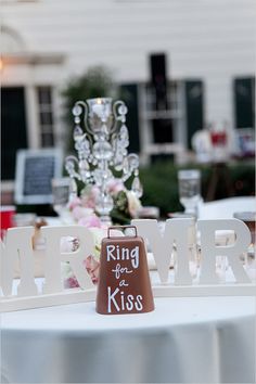 a white table topped with a brown and white bell next to a sign that says king of the kiss