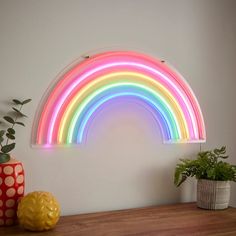 a rainbow shaped light is on the wall next to a potted plant and vase