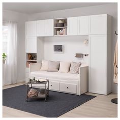 a living room filled with furniture and lots of white cupboards next to a window