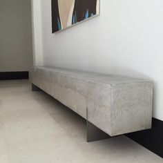 a concrete bench sitting in front of a painting on the wall next to a black and white floor