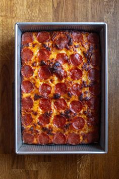 pepperoni pizza sitting in a pan on top of a wooden table