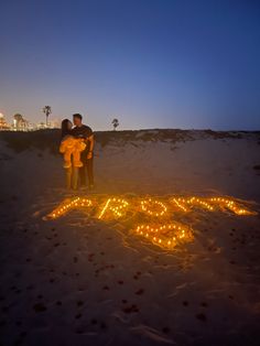 a man and woman standing in the sand next to a sign that says love