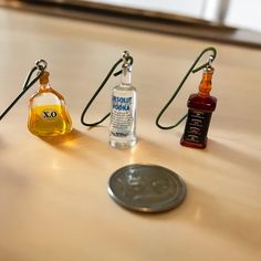 three bottles of alcohol sitting on top of a table next to a coin and lanyard