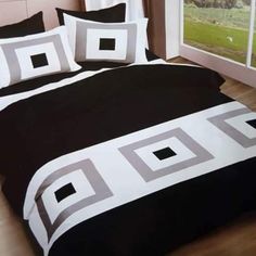 a bed with black and white bedspreads in front of a large open window