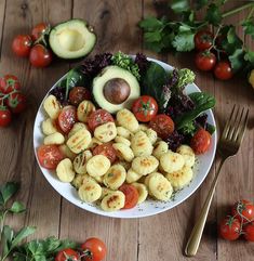 a white plate topped with lots of veggies next to a fork and knife