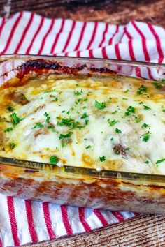 a casserole dish with meat, cheese and parsley on a red and white towel