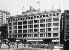 an old black and white photo of a building with people walking in front of it