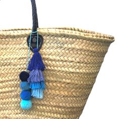 a large woven basket with tassels hanging from it's sides and two pom poms attached to the handles