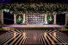 a stage decorated with flowers and greenery for a wedding or special event at night