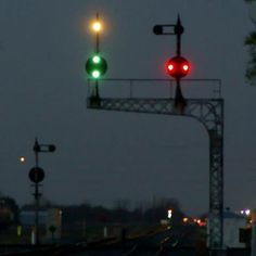 two green and red traffic lights at an intersection in the dark night time with trees on either side