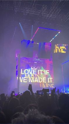 the crowd is at a concert with their hands up in front of an electronic screen