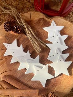 three white stars are sitting on a wooden board next to pine cones and twine