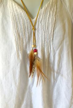 "Add a boho look to your outfit with this simplistic long natural necklace. Handmade to order by me. Deerskin leather cord is used. It flows better, flexible, and soft to the touch. 2 clusters of natural feathers with wooden beads hang below the knot. Customize this necklace by choosing your shade of accent bead color. Please see last listing photo for color options. There is one colored bead on the necklace. Circumference of the necklace from 24-30\". Please use the listing variation to choose. Bohemian Lariat Long Necklace For Festival, Bohemian Natural Beaded Necklaces, Bohemian Natural Beaded Necklaces For Festivals, Natural Bohemian Beaded Necklace For Festival, Brown Necklace For Summer Festivals, Bohemian Natural Beaded Necklace For Festival, Adjustable Bohemian Long Necklace For Festivals, Adjustable Natural Bohemian Necklaces, Adjustable Bohemian Necklaces In Natural Color