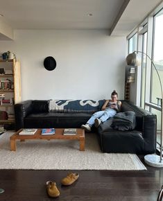 a man sitting on top of a black couch in a living room