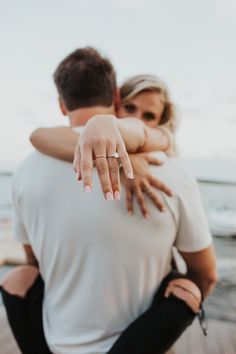 a man and woman hugging each other on the beach with their hands wrapped around them