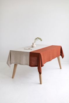 a table with an orange cloth on it and a white vase sitting on top of it