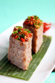 two pieces of food sitting on top of a green leaf covered plate next to another piece of food