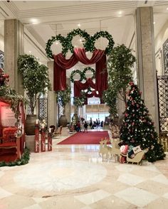 christmas decorations are displayed in the lobby of a large, ornate building with red and white decor