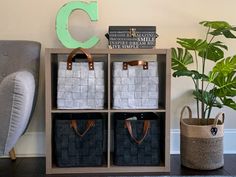 three baskets are stacked on top of each other in front of a gray chair and a green letter