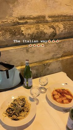 two plates of food on a table next to bottles of wine and glasses with water