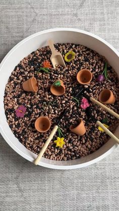 a white bowl filled with lots of different types of sticks and bowls on top of it