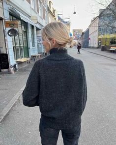 a woman standing in the middle of an empty street with her back to the camera