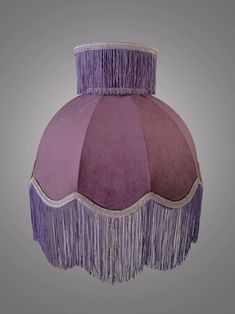 a purple lamp shade with fringes hanging from it's sides on a gray background